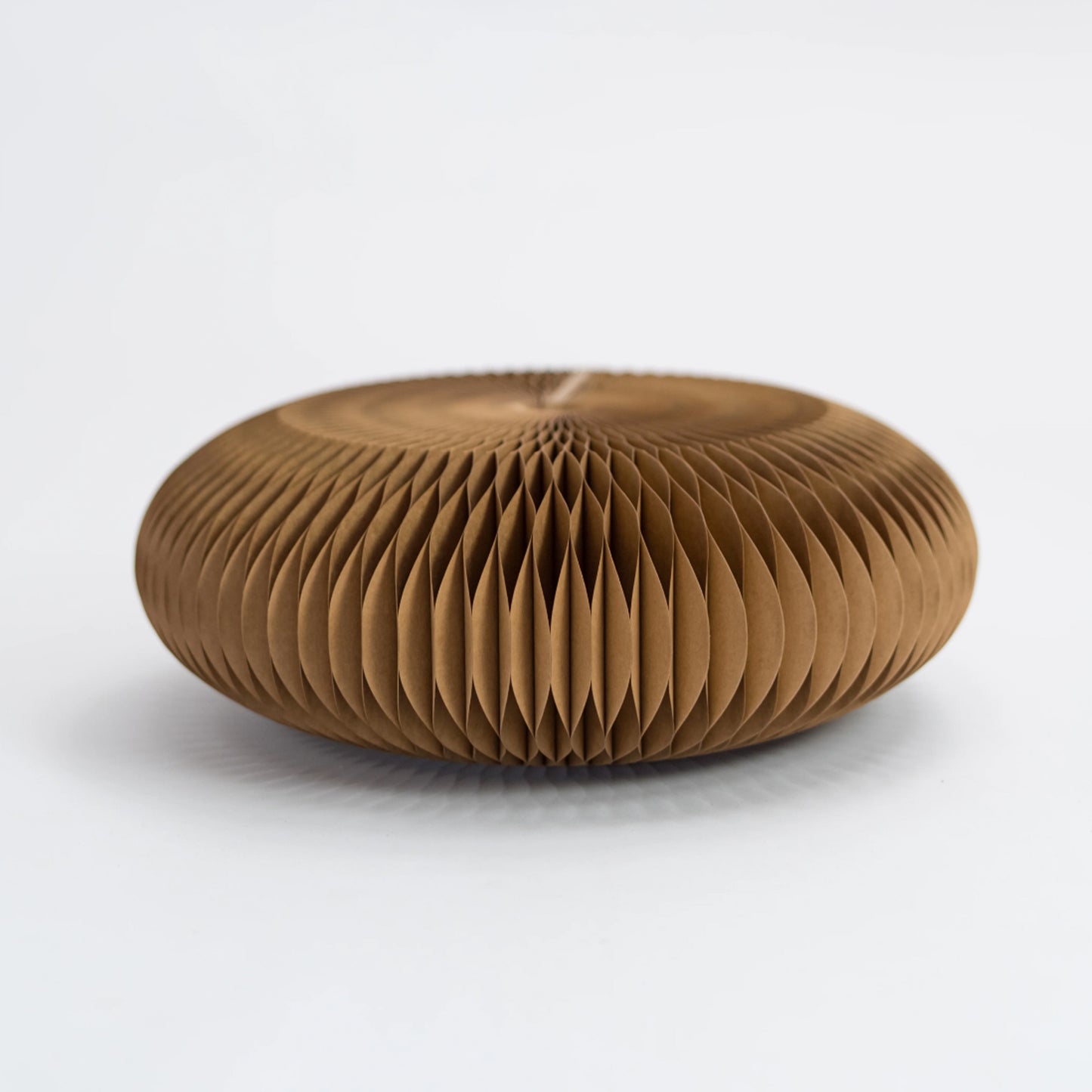 Brown origami honeycomb paper footstool on a white background