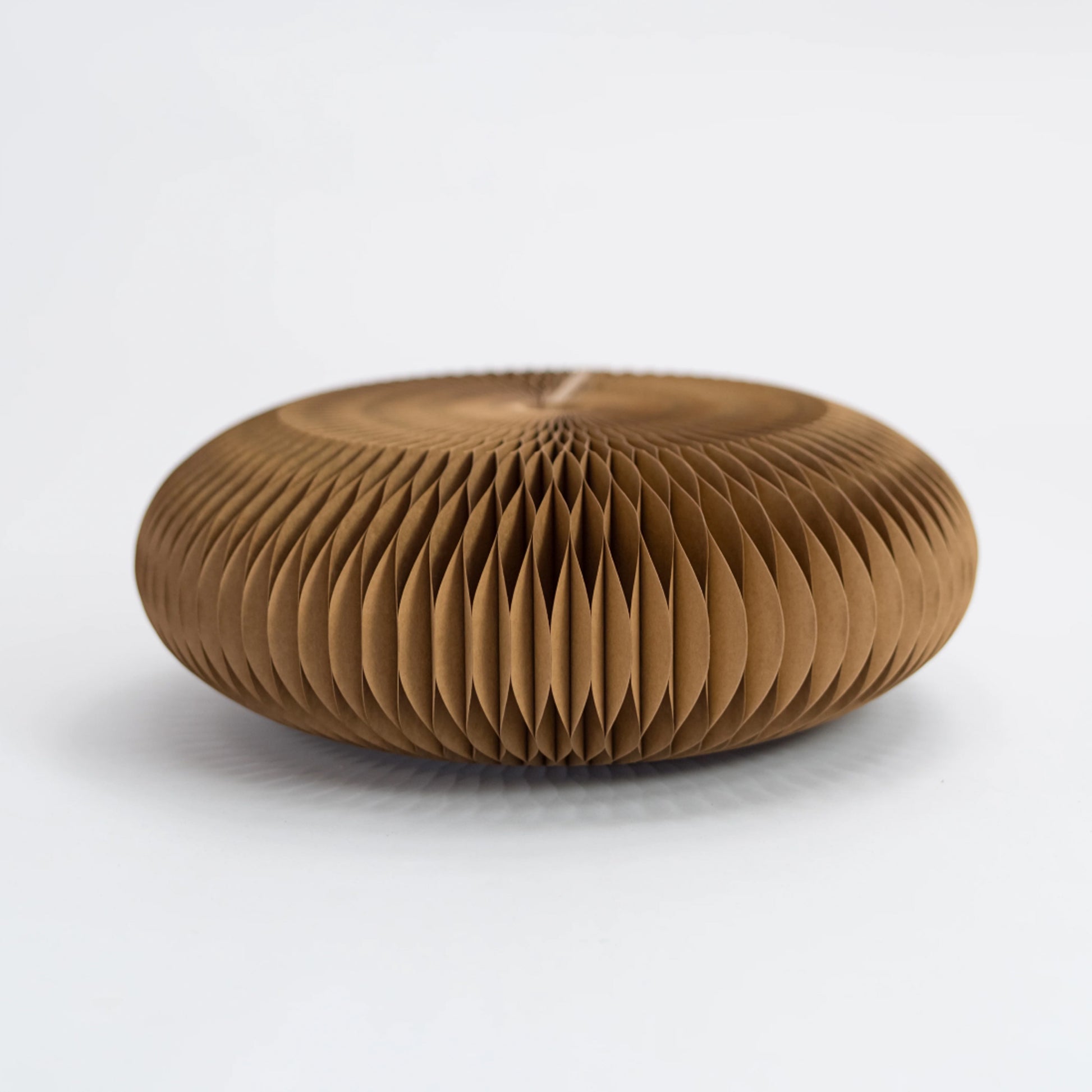 Brown origami honeycomb paper footstool on a white background