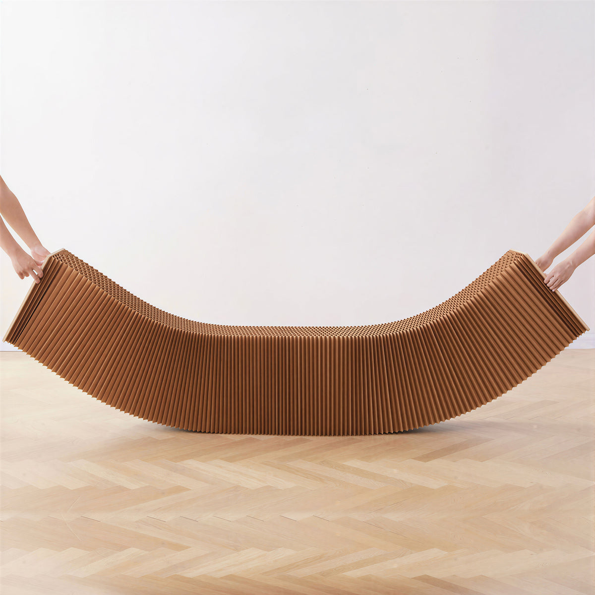 Hands expanding a curved brown honeycomb paper bench to adapt multi-person seating to different space shapes