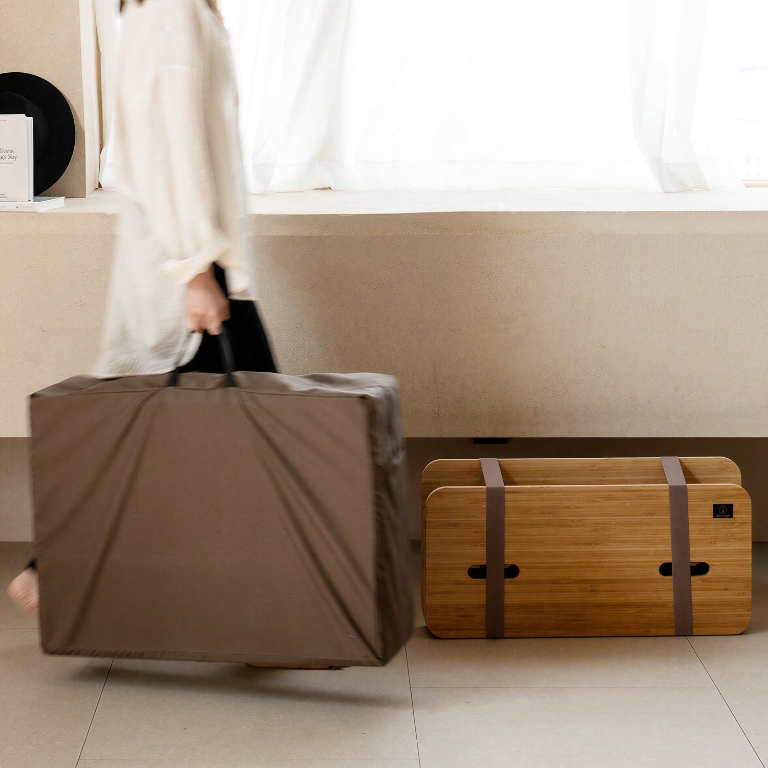 Person carrying compact packaged paper bed for temporary accommodation – reducing operational burden of temporary setups