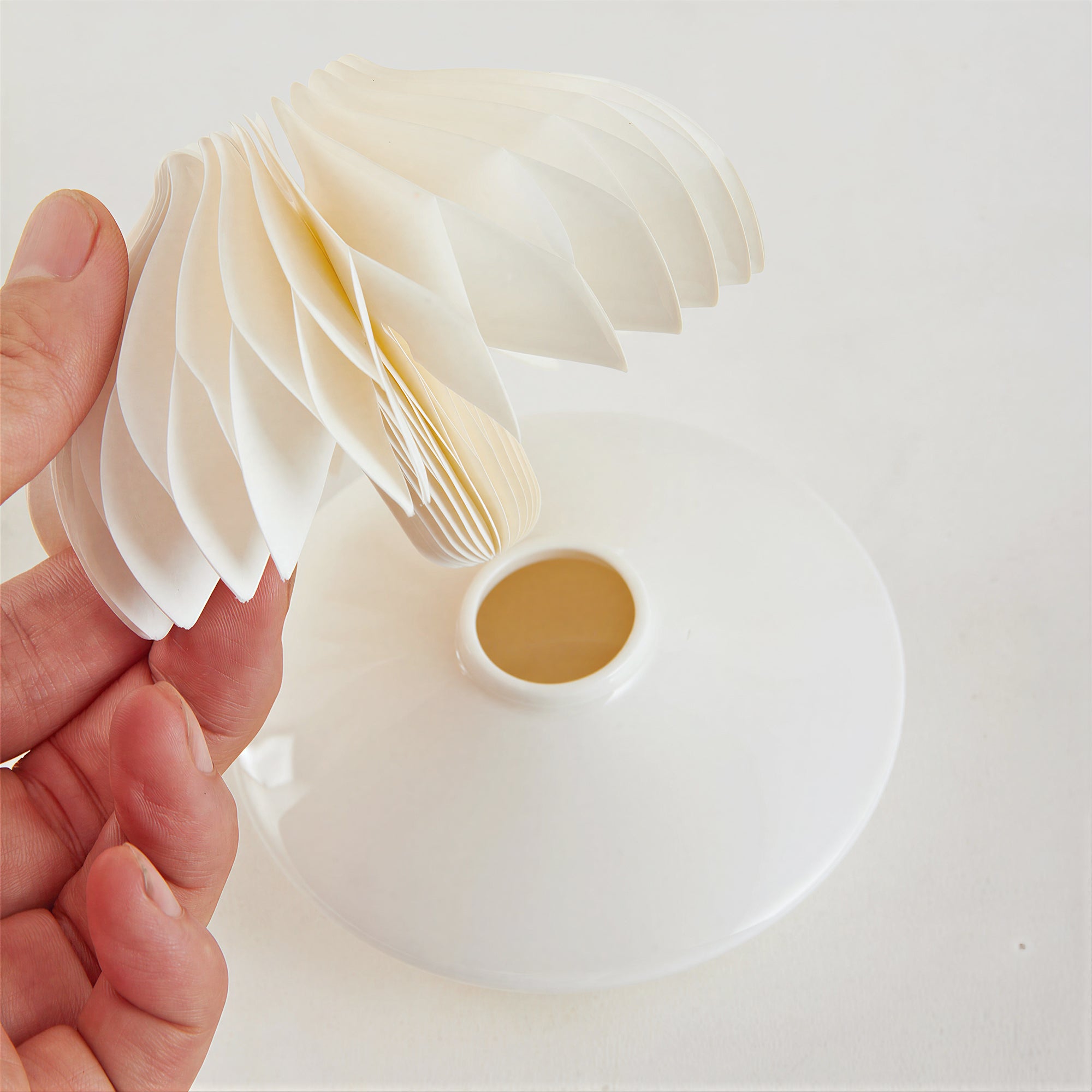Hand holding expandable white honeycomb paper diffuser structure – core benefits of paper fragrance diffusers