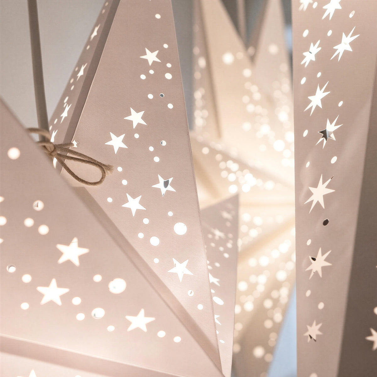 Close-up of illuminated paper star lampshades with cutout patterns