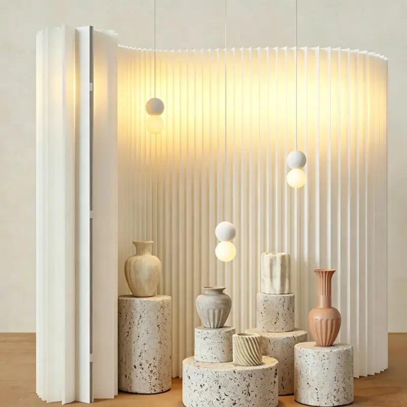 Minimalist curved pleated paper backdrop divider with stone plinths and ceramic vases for trade show